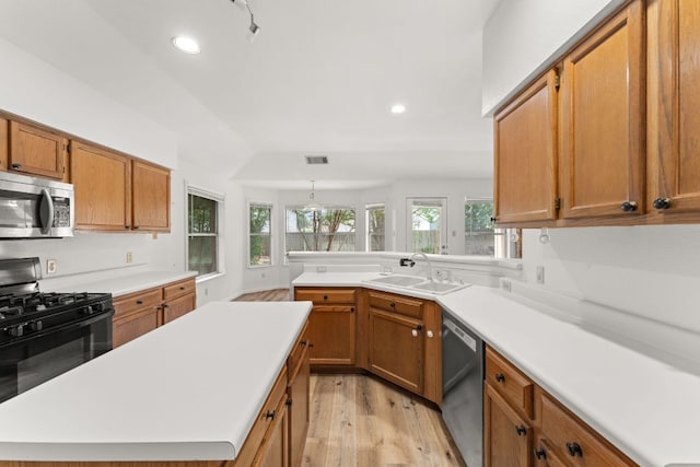 kitchen with appliances with stainless steel finishes, a sink, light wood-style flooring, light countertops, and brown cabinetry