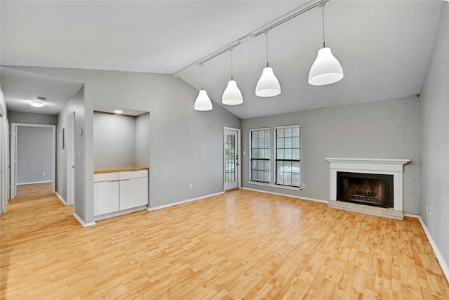 1202 Thorpe Ln Unit 508, San Marcos, TX 78666 - unfurnished living room with light wood-type flooring, vaulted ceiling, baseboards, and a fireplace with raised hearth