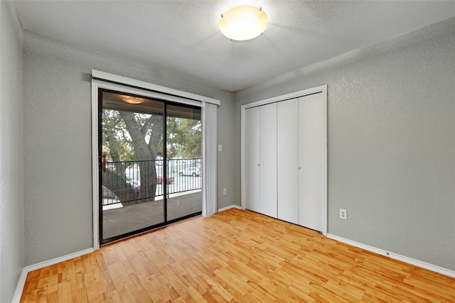 1202 Thorpe Ln Unit 508, San Marcos, TX 78666 - unfurnished bedroom featuring access to exterior, wood finished floors, a textured wall, baseboards, and a textured ceiling