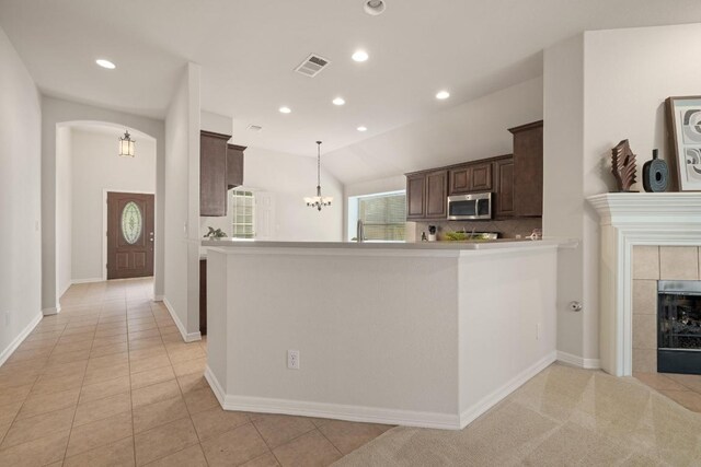 765 Bent Wood Pl, Round Rock, TX 78665 - kitchen featuring stainless steel microwave, dark brown cabinetry, recessed lighting, a chandelier, and a tile fireplace