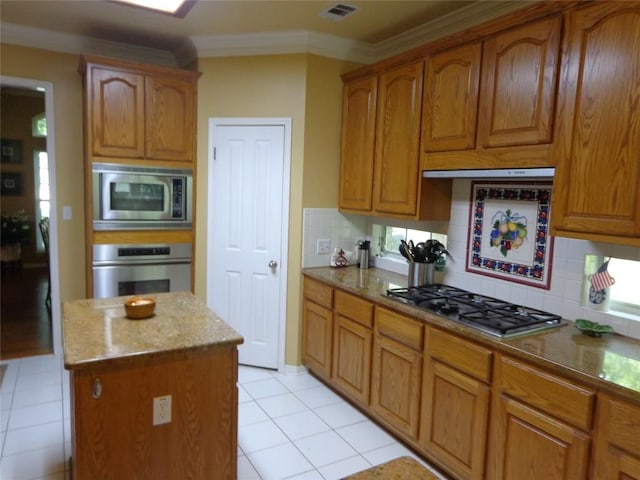 4003 Wyman Cv, Round Rock, TX 78681 - kitchen with stainless steel appliances, ornamental molding, tasteful backsplash, light tile patterned floors, and a center island