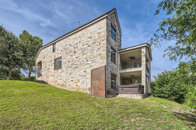 205 Sebastians Run, Austin, TX 78738 - view of side of property with a ceiling fan, a hot tub, stone siding, a yard, and a balcony