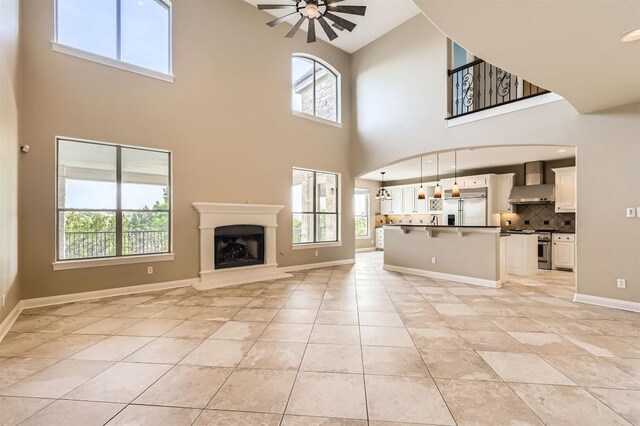 205 Sebastians Run, Austin, TX 78738 - unfurnished living room with a ceiling fan, high vaulted ceiling, light tile patterned floors, and a fireplace with raised hearth