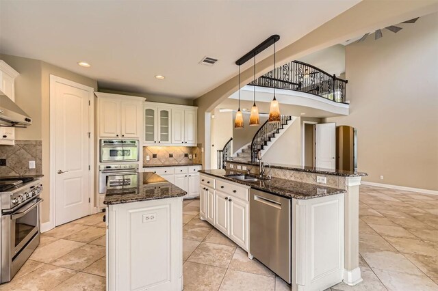 205 Sebastians Run, Austin, TX 78738 - kitchen with an island with sink, appliances with stainless steel finishes, backsplash, arched walkways, and recessed lighting