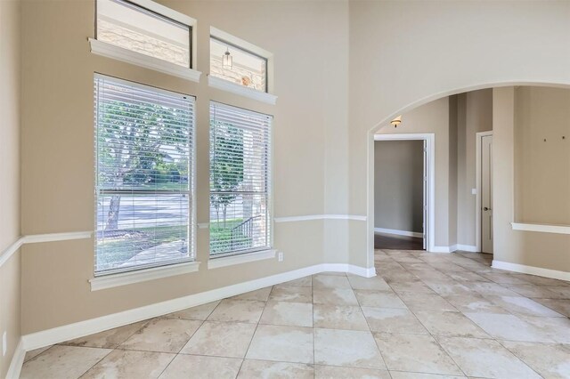 205 Sebastians Run, Austin, TX 78738 - spare room with plenty of natural light, a towering ceiling, light tile patterned floors, and arched walkways