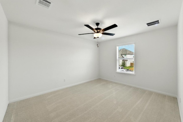 spare room featuring light colored carpet, baseboards, and ceiling fan