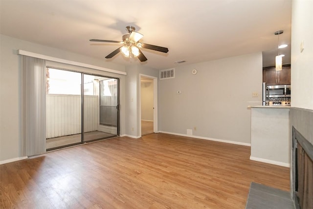 3115 Helms St Unit 115, Austin, TX 78705 - unfurnished living room with a ceiling fan, light wood finished floors, and a fireplace with flush hearth