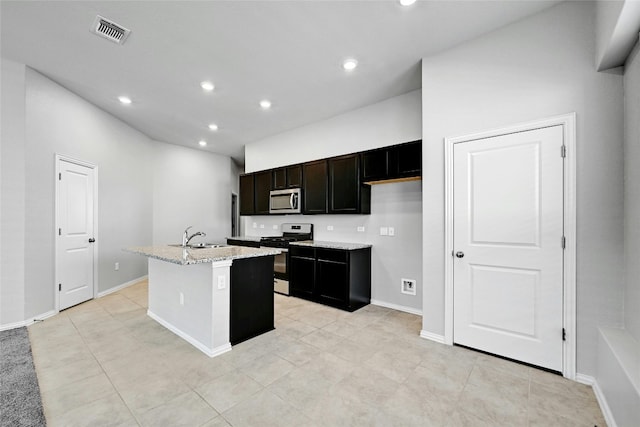 12725 Bloomington Dr Unit 129, Austin, TX 78748 - kitchen with appliances with stainless steel finishes, a kitchen island with sink, recessed lighting, a sink, and light stone counters