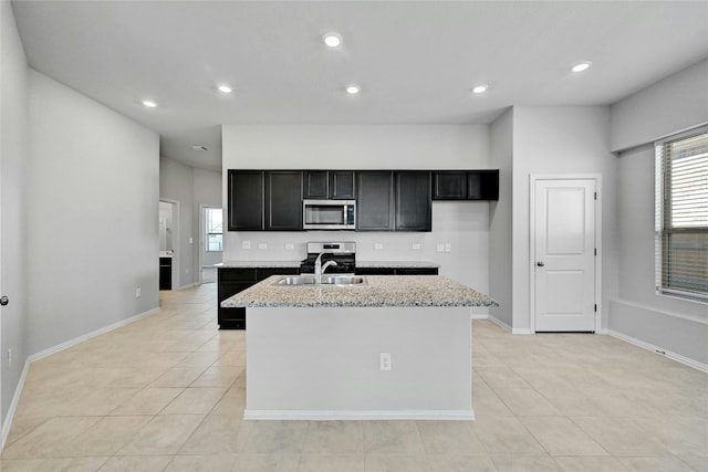 12725 Bloomington Dr Unit 129, Austin, TX 78748 - kitchen with stainless steel appliances, light tile patterned floors, an island with sink, recessed lighting, and baseboards