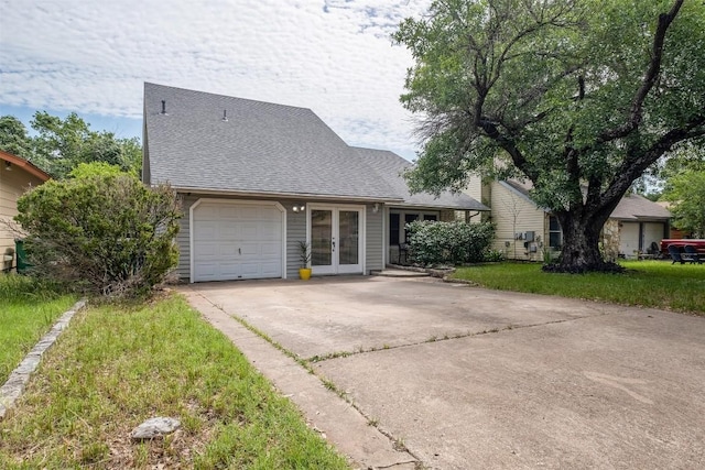 7503 Islander Dr, Austin, TX 78749 - view of front of house with french doors, concrete driveway, a garage, roof with shingles, and a front lawn