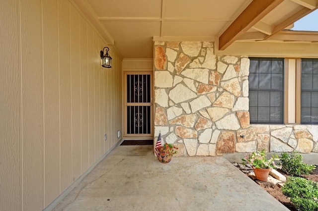 entrance to property featuring stone siding and a patio area