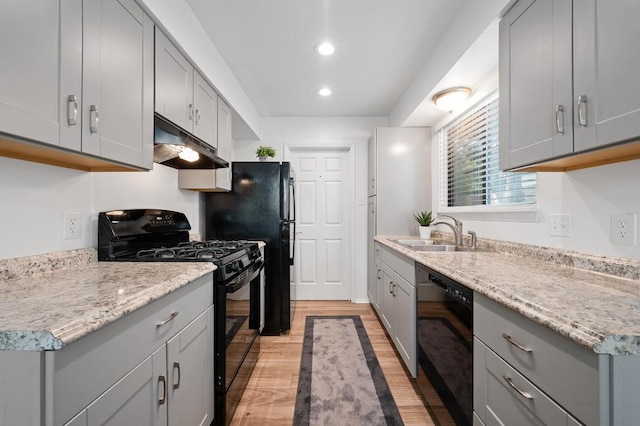5406 Fence Row, Austin, TX 78744 - kitchen featuring black appliances, under cabinet range hood, gray cabinets, a sink, and light wood finished floors