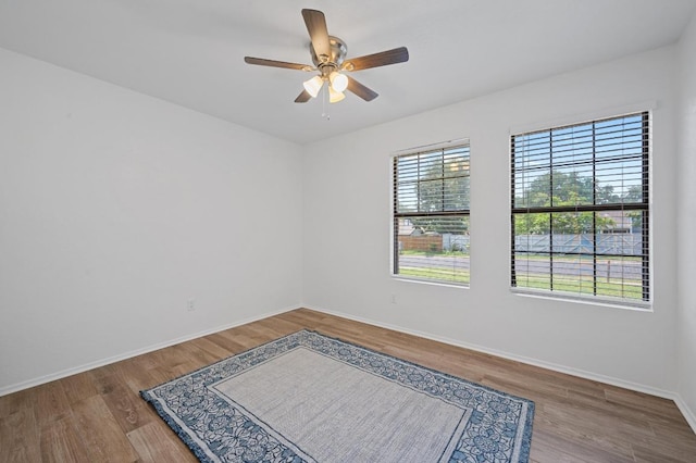 unfurnished room with ceiling fan, wood finished floors, and baseboards