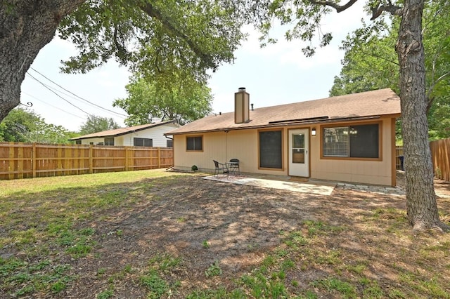 rear view of property with a chimney, a fenced backyard, and a patio