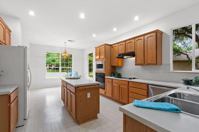 106 Ranch House Cv, Georgetown, TX 78633 - kitchen featuring black appliances, a kitchen island, plenty of natural light, brown cabinets, and recessed lighting