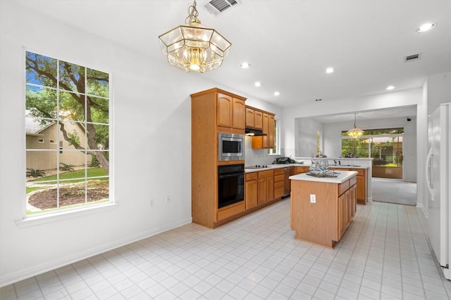 106 Ranch House Cv, Georgetown, TX 78633 - kitchen with oven, stainless steel microwave, freestanding refrigerator, light countertops, and a kitchen island