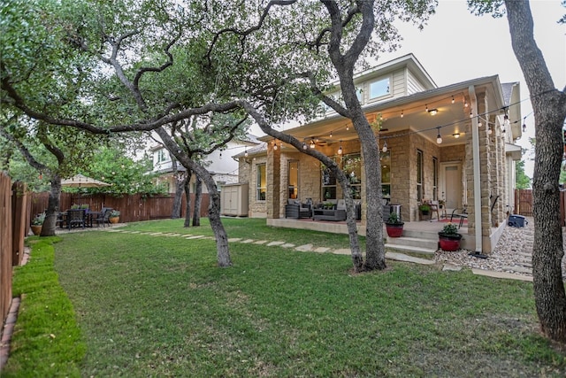 back of property featuring a patio area, stone siding, a ceiling fan, and an outdoor living space