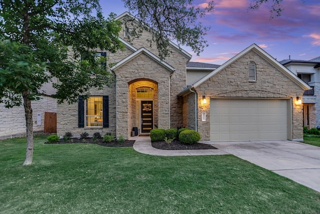 french country home with stone siding, an attached garage, driveway, and a front lawn