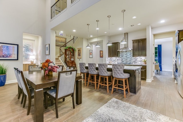dining space with stairway, light wood-style floors, baseboards, and recessed lighting