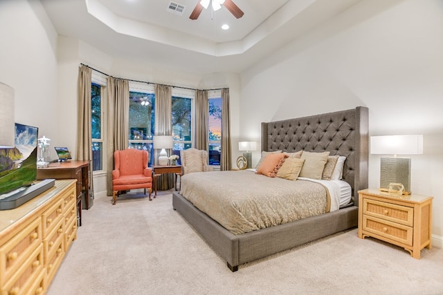 bedroom with light carpet, a tray ceiling, a ceiling fan, and baseboards