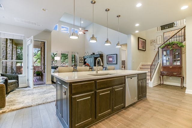 kitchen with open floor plan, dishwasher, a sink, light wood-type flooring, and light countertops