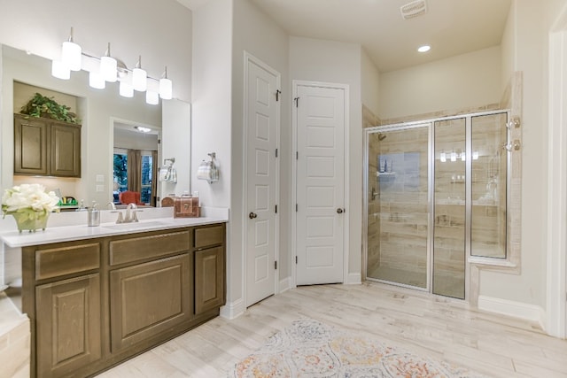 full bath with a shower stall, vanity, wood finished floors, recessed lighting, and baseboards