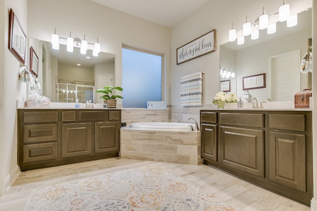 full bathroom featuring a stall shower, a garden tub, two vanities, and wood finished floors