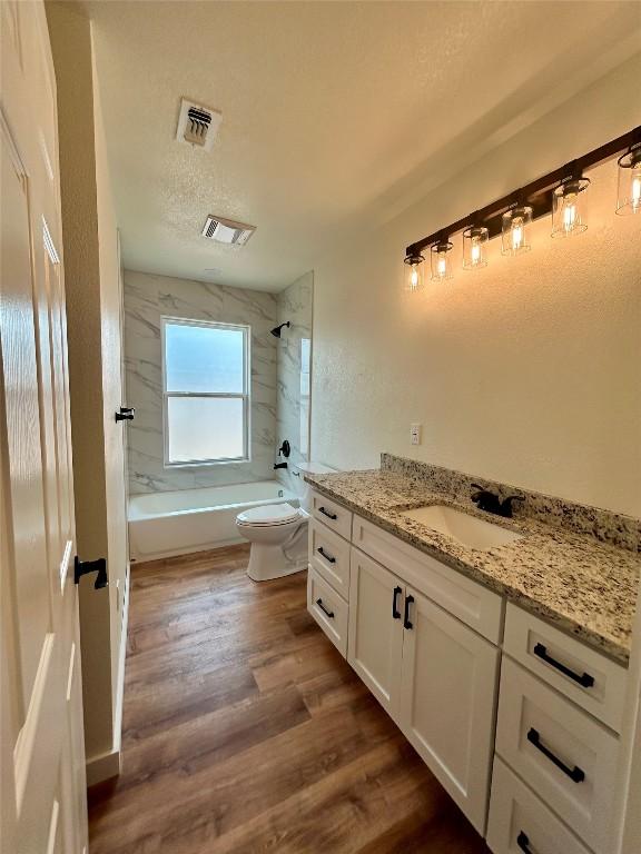1127 Greenhill Dr, Canyon Lake, TX 78133 - bathroom with vanity, washtub / shower combination, wood finished floors, and a textured ceiling