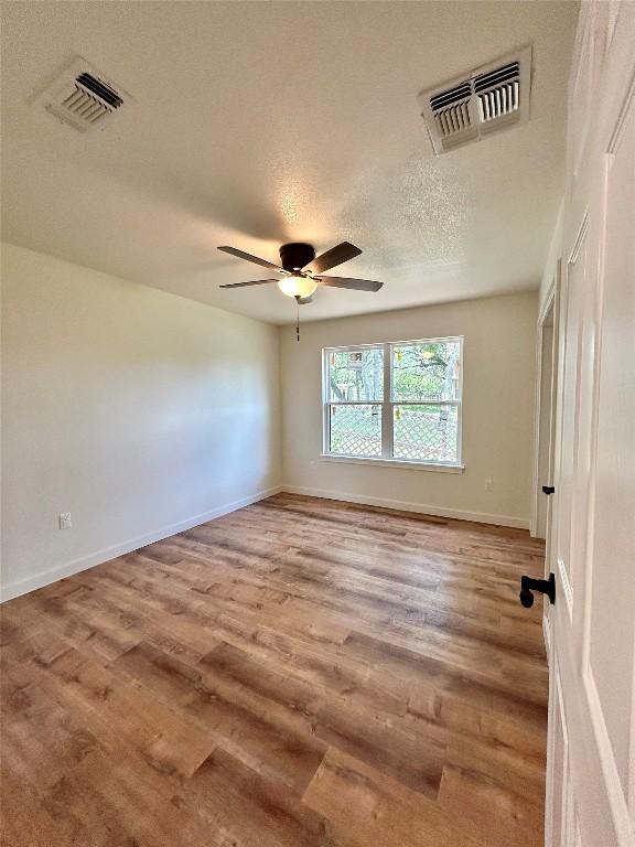 1127 Greenhill Dr, Canyon Lake, TX 78133 - empty room with wood finished floors, a ceiling fan, and a textured ceiling