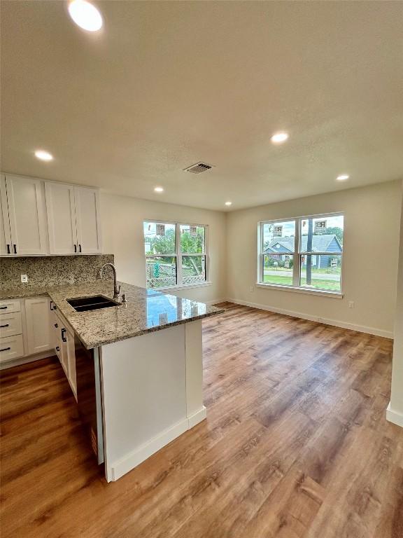 1127 Greenhill Dr, Canyon Lake, TX 78133 - kitchen with recessed lighting, white cabinets, light stone counters, light wood-type flooring, and backsplash