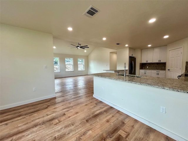 1127 Greenhill Dr, Canyon Lake, TX 78133 - kitchen featuring white cabinets, light wood finished floors, recessed lighting, light stone countertops, and refrigerator
