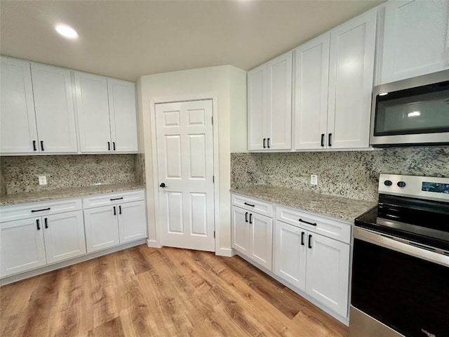 1127 Greenhill Dr, Canyon Lake, TX 78133 - kitchen featuring stainless steel appliances, tasteful backsplash, light wood-type flooring, white cabinets, and light stone countertops