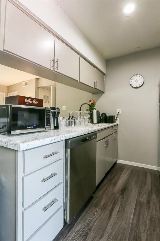 101 E 33rd St Unit 107, Austin, TX 78705 - kitchen featuring stainless steel appliances, dark wood-style floors, baseboards, a sink, and white cabinetry