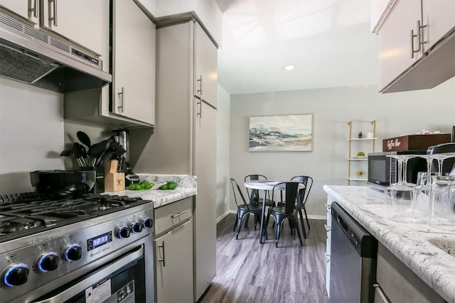 101 E 33rd St Unit 107, Austin, TX 78705 - kitchen with appliances with stainless steel finishes, under cabinet range hood, dark wood-style flooring, baseboards, and gray cabinets