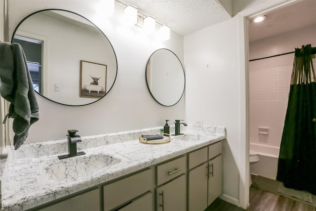 101 E 33rd St Unit 107, Austin, TX 78705 - bathroom with wood finished floors, double vanity, shower / bath combo with shower curtain, toilet, and a textured ceiling