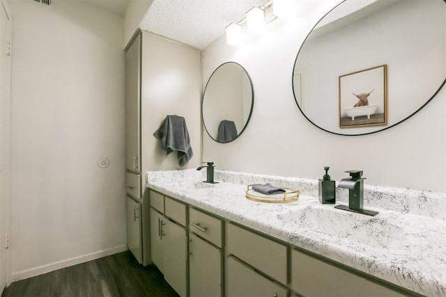 101 E 33rd St Unit 107, Austin, TX 78705 - bathroom featuring wood finished floors, double vanity, baseboards, and a textured ceiling