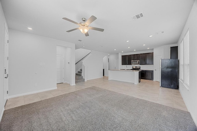 unfurnished living room featuring light tile patterned floors, stairs, ceiling fan, a sink, and recessed lighting