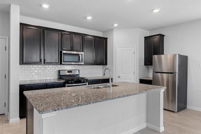 kitchen featuring stainless steel appliances, a sink, stone counters, backsplash, and recessed lighting