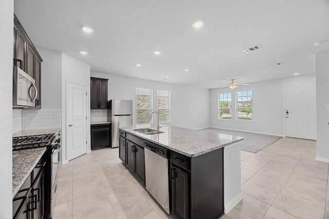 kitchen with stainless steel appliances, a sink, recessed lighting, a ceiling fan, and backsplash