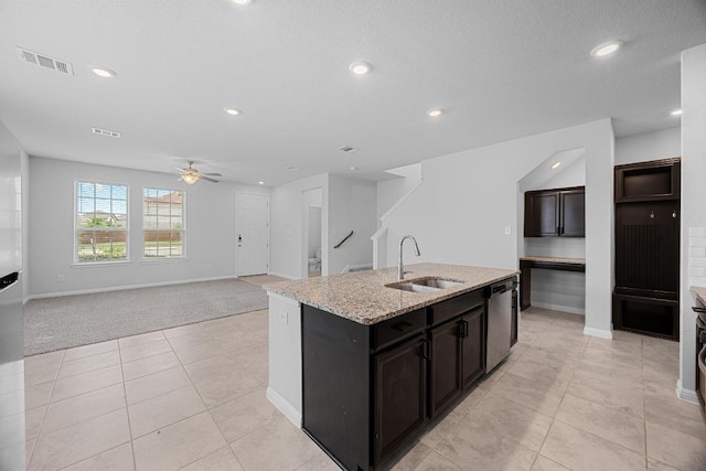 kitchen with a sink, light colored carpet, dishwasher, ceiling fan, and a center island with sink