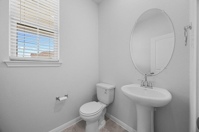bathroom with baseboards, toilet, and tile patterned floors