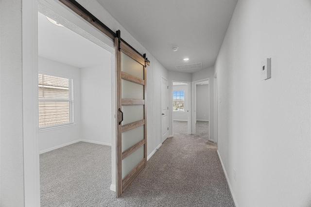 corridor with a barn door, carpet flooring, baseboards, and recessed lighting