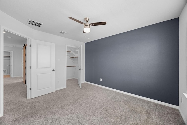 unfurnished bedroom featuring carpet, baseboards, and a walk in closet