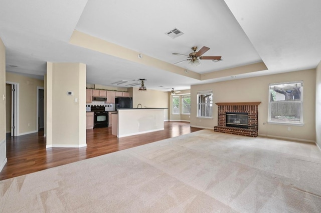 5705 Marchmont Ln, Austin, TX 78749 - unfurnished living room featuring ceiling fan, carpet floors, a tray ceiling, baseboards, and wood finished floors