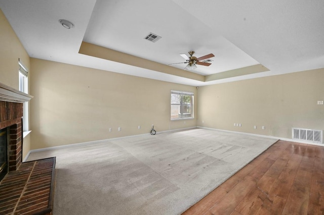 5705 Marchmont Ln, Austin, TX 78749 - unfurnished living room with a tray ceiling, baseboards, a ceiling fan, a fireplace, and wood finished floors