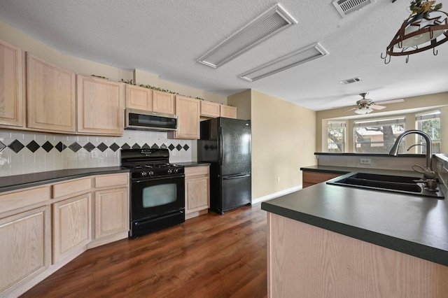 5705 Marchmont Ln, Austin, TX 78749 - kitchen featuring black appliances, light brown cabinetry, a sink, dark countertops, and a textured ceiling