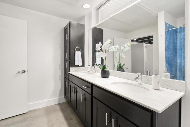 full bath with finished concrete floors, baseboards, and double vanity