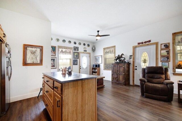 472 Mountain View Dr, Bandera, TX 78003 - kitchen featuring ceiling fan, dark wood-type flooring, brown cabinets, baseboards, and a center island