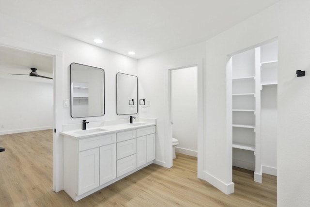 full bathroom with wood finished floors, a walk in closet, toilet, and recessed lighting