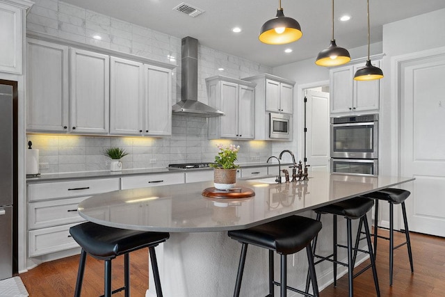 225 Cimarron Hills Trl E, Georgetown, TX 78628 - kitchen featuring wall chimney exhaust hood, stainless steel appliances, backsplash, a kitchen bar, and decorative light fixtures